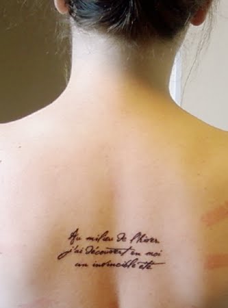 Shoulder tattoo saying “un jour a la fois”, french