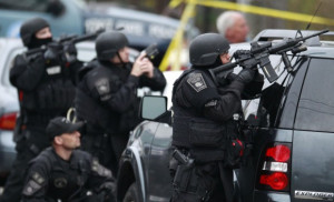 Police in tactical gear surround an apartment building while looking ...