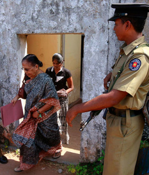 Ethnic Tamil women walk out from a registration centre as policemen ...