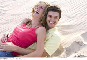 Young_couple_relaxing_in_sand_laughing_17233.jpg