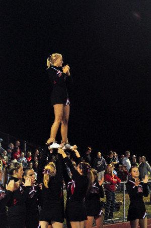 Varsity football cheerleaders perform a stunt during a football game ...