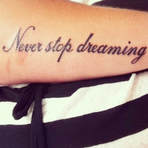 Never stop dreaming” quote tattoo on girls arm