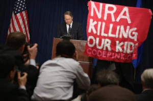 demonstrator from CodePink holds up a banner Friday as Wayne LaPierre ...