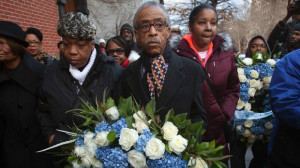 Civil rights activist Reverend Al Sharpton carries a wreath, flanked ...