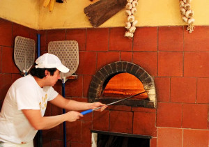 Taking out the pizza very gently from the wood fired brick oven.