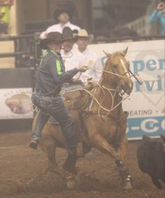 Tuff Cooper dismounts his horse during the tie down roping event at ...