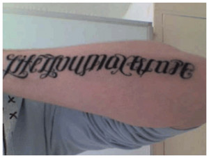 Life You May Escape Death You May - Ambigram Tattoo On Left Arm