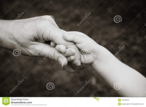Grandparent holding hands with grandchild in black and white.