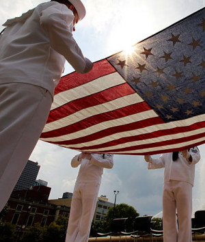 Navy sailors in the honor guard fold a flag before the ...