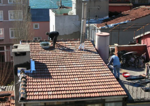 Watching cement liberally applied on top of roof tiles...]