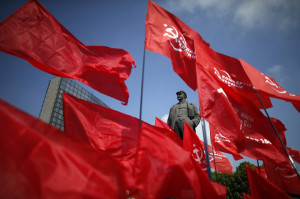 Participants wave communist flags near a statue of Soviet leader ...