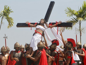 portraying Jesus Christ, is raised on a wooden cross by a group of men ...