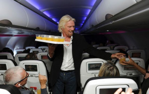 Virgin Group founder Sir Richard Branson serves travelers abroad a ...