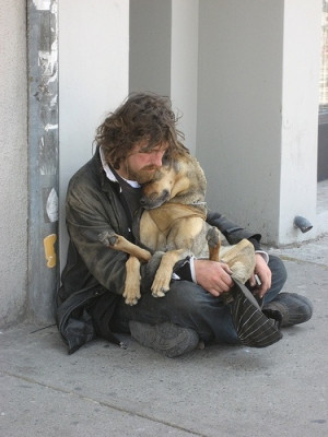 Homeless man cuddling dog