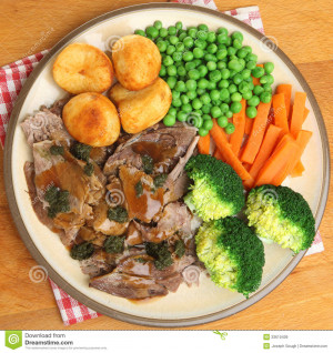 Roast lamb dinner with vegetables gravy and mint sauce.