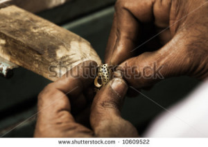 holding an unfinished 22 carat gold earring in his hard working hands ...