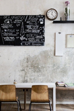 cement walls, chalk board, wooden chairs
