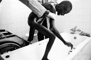 man ravaged by AIDS is bathed at a hospice in Zambia
