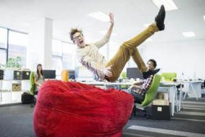 Businessman jumping into beanbag chair in office - Robert Daly ...