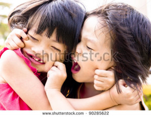 Playful Asian siblings pulling each other faces.