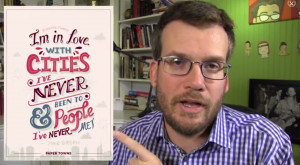 Author John Green points to a poster that attributes a quote to one of ...