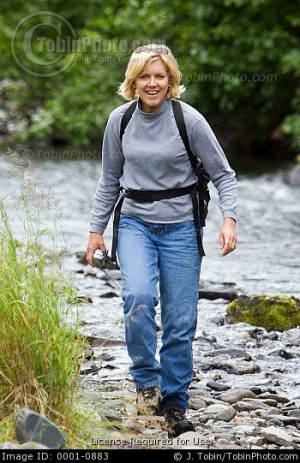 woman hiking along a river in Alaska.