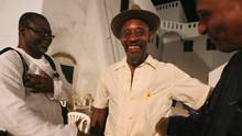 Poet Linton Kwesi Johnson (C) talks with friends at Elmina castle in ...