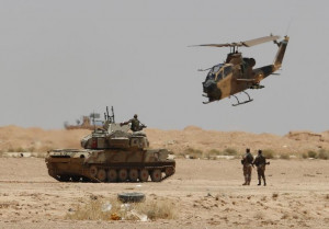 Jordanian military helicopter flies over an armored vehicle near the ...