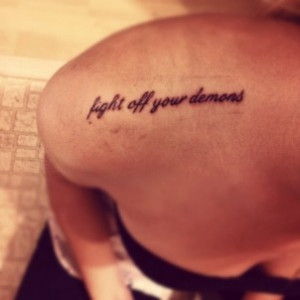 fight off your demons” quote tattoo on girls shoulder