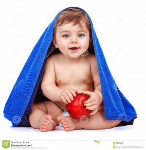 Cute baby boy covered with blue towel holding in hands red fresh apple ...
