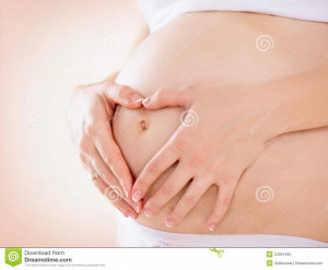 Pregnant Woman holding hands in a heart shape on her baby bump.