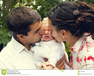 Parents kissing and consoling their crying baby in her christening day ...