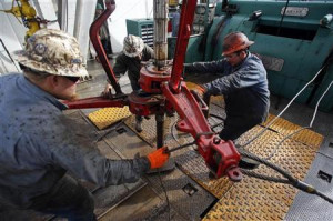 Roughnecks wrestle pipe on a True Company oil drilling rig outside ...