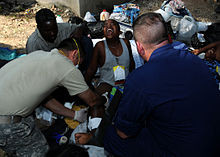 Medical personnel aid a suffering woman after the 2010 Haiti ...