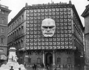 ... stone Mussolini face looking down surrounded by a sea of 