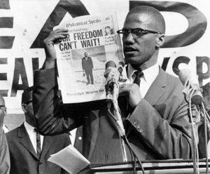 Malcolm X holds newspaper