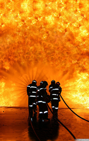 Incredible orange blaze silhouettes firefighters spraying water ...