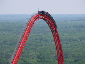 Cars travel over the top of the lift hill and begin their descent on ...