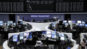 Traders are pictured at their desks in front of the German share price ...