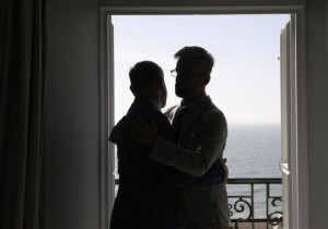 Gay couple Andrew Wale (R) and Neil Allard embrace in their hotel room ...