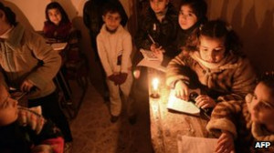 children attend an early morning class by candle light due to the lack ...