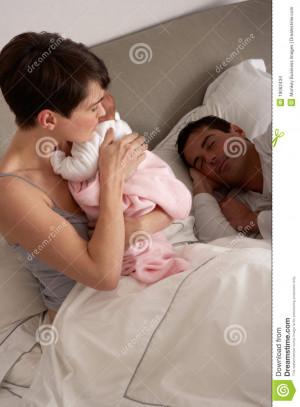 Mother Cuddling Newborn Baby In Bed At Home.