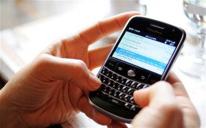 woman using a Blackberry phone to send and receive emails and text ...