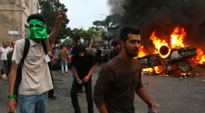 Smoke billows from a car set on fire by supporters of defeated Iranian ...