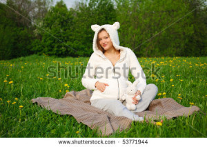 Beautiful funny pregnant woman on field with dandelions in a suit lamb ...