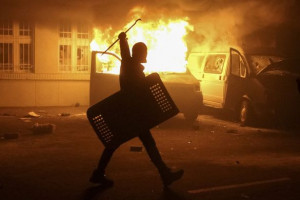 protester passing burning vans and the destroyed building of Ukraine ...