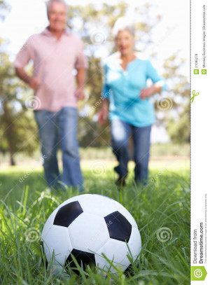 Senior couple playing football in countryside.