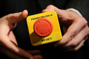 An assistant shows the block with a red button marked 