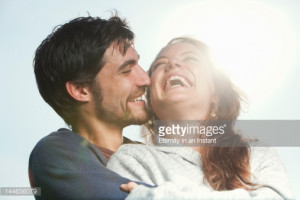 Stock Photo : Young couple laughing together, hugging outdoors