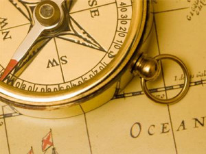 Gold compass on a vintage world map